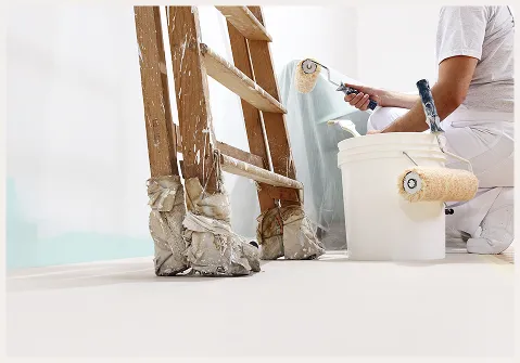 Maler hockt vor der Wand und arbeitet